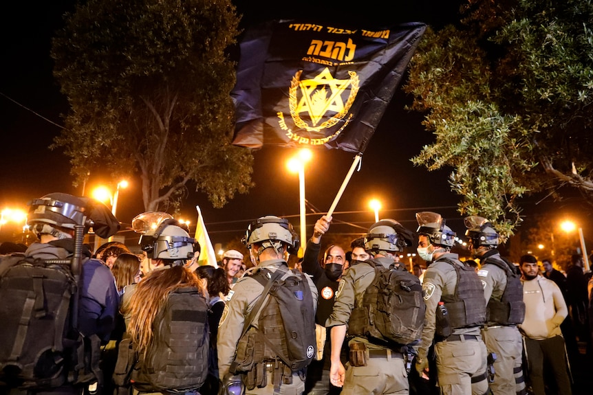 Israeli police block protesters waving banners with Hebrew slogans