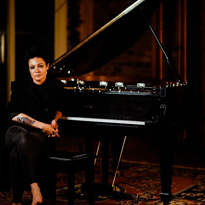 Photo of singer Sarah McLeod seated near a grand piano