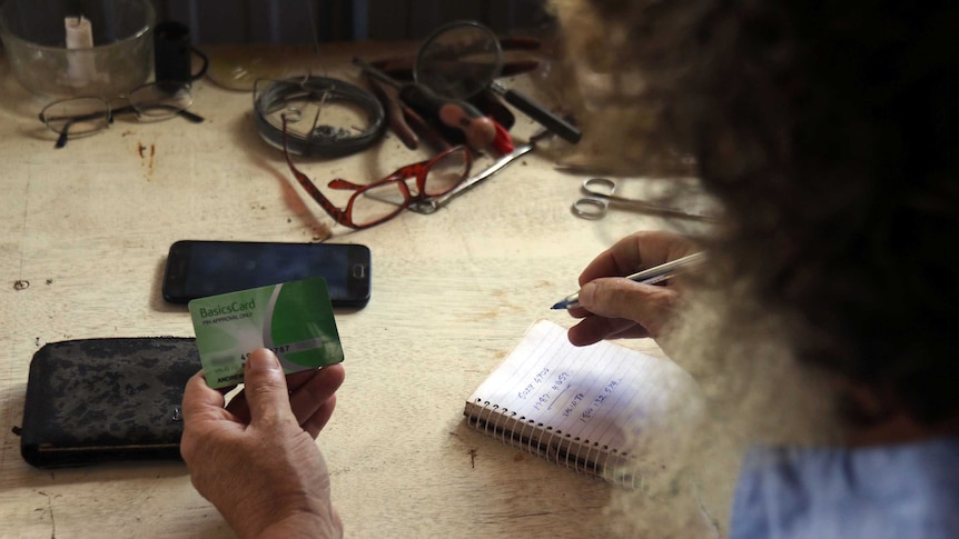 Andrew Walton holds his card and makes calculations on a notepad as the camera looks over his shoulder