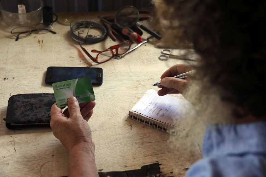 Andrew Walton holds his card and makes calculations on a notepad as the camera looks over his shoulder