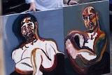 Two self-portraits are held up side by side.