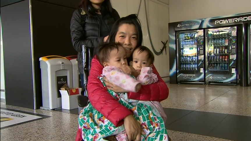 Mother Bhumchu Zangmo hugs her twins Nima and Dawa as she is wheeled through Melbourne Airport.