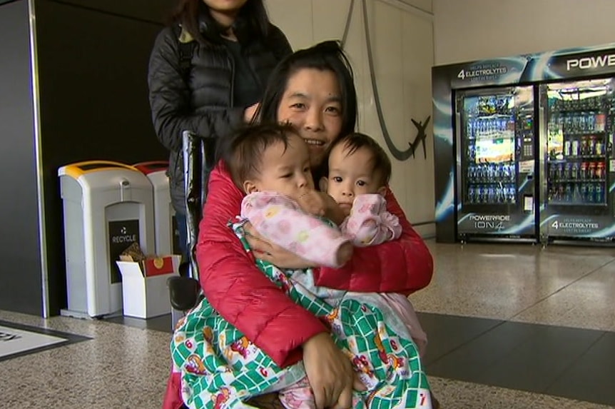 Mother Bhumchu Zangmo hugs her twins Nima and Dawa as she is wheeled through Melbourne Airport.