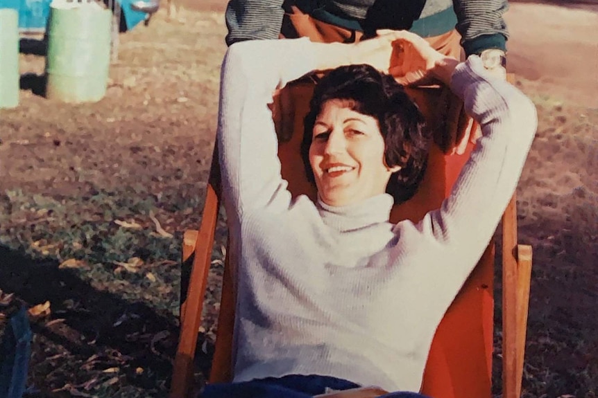 A woman smiling at the camera while lounging on a camping chair.