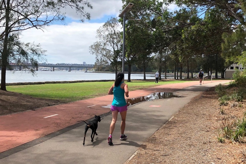 The back of a woman jogging next to Sydney Harbour.