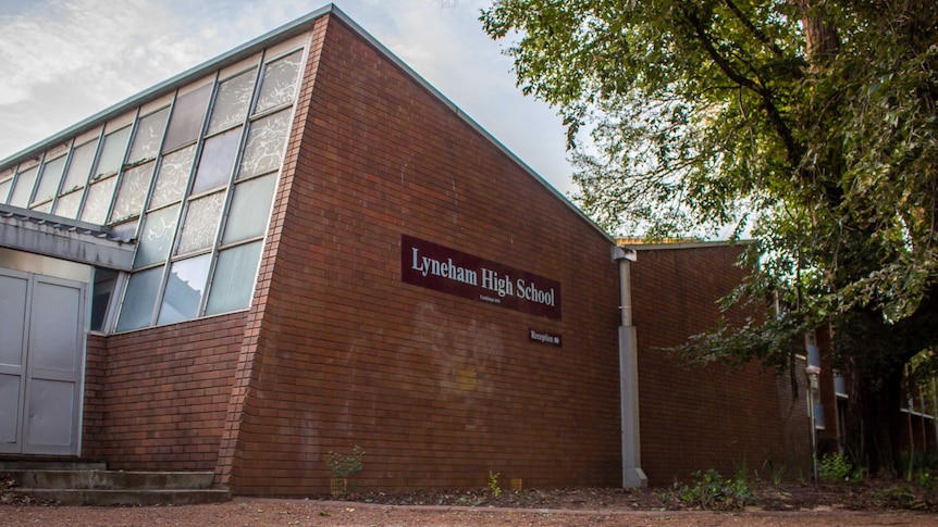 The side of a brick building with a sign that reads 'Lyneham High School'.