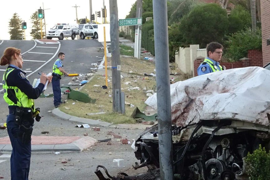 Police officers near a white car which crashed into a street sign.