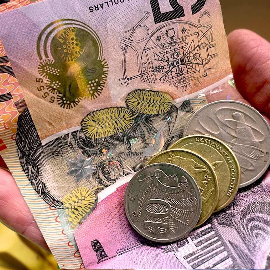 Close up of a hand holding cash money and coins over images of fruit and cup of coffee