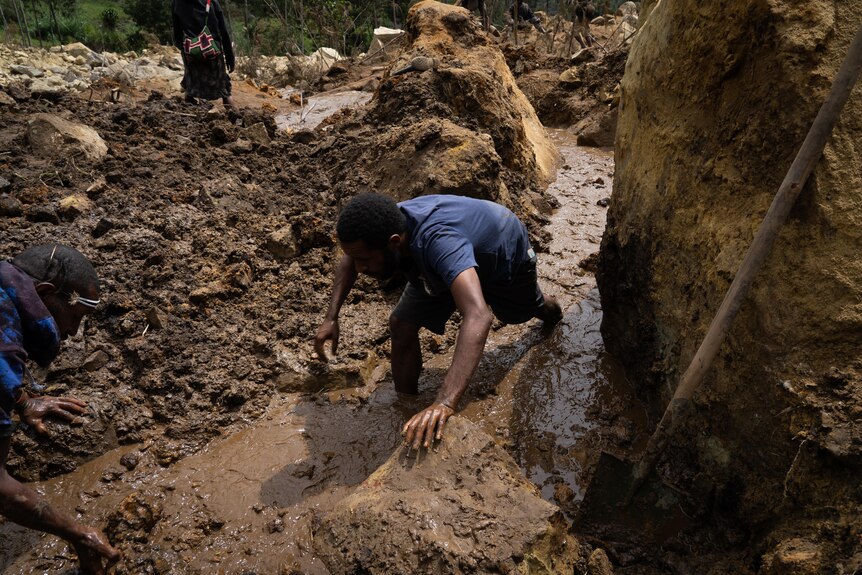 A man knee deep in a muddy area 