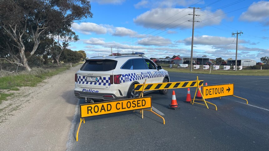 A police car and road closure signs on a highway.