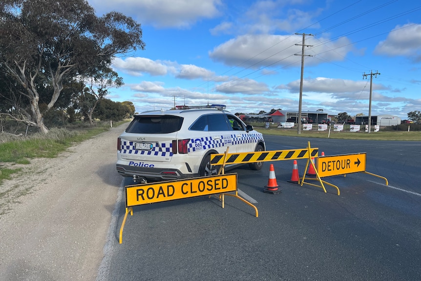 A police car and road closure signs on a highway.
