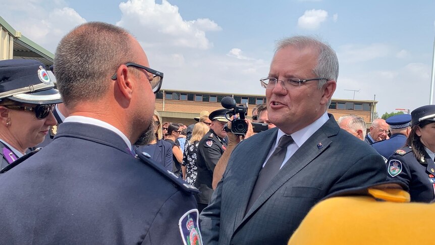 Prime Minister Scott Morrison speaks with senior RFS leaders among a crowd of people at a funeral.