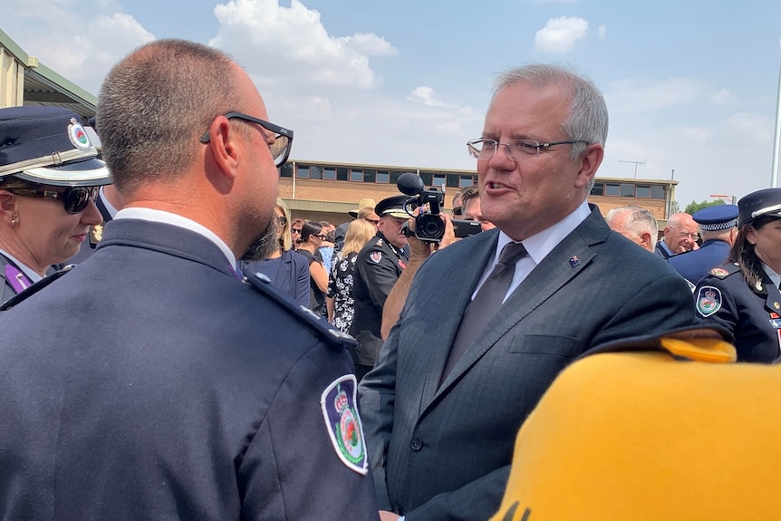 Prime Minister Scott Morrison speaks with senior RFS leaders among a crowd of people at a funeral.