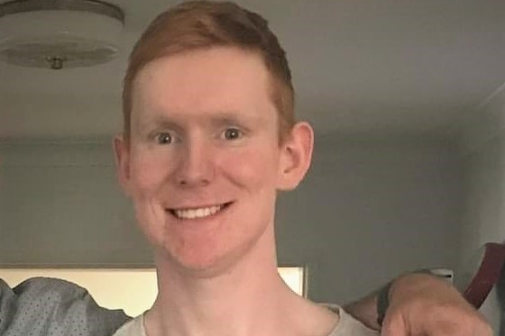 A man with pale skin and orange hair smiles for the camera