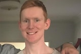 A man with pale skin and orange hair smiles for the camera