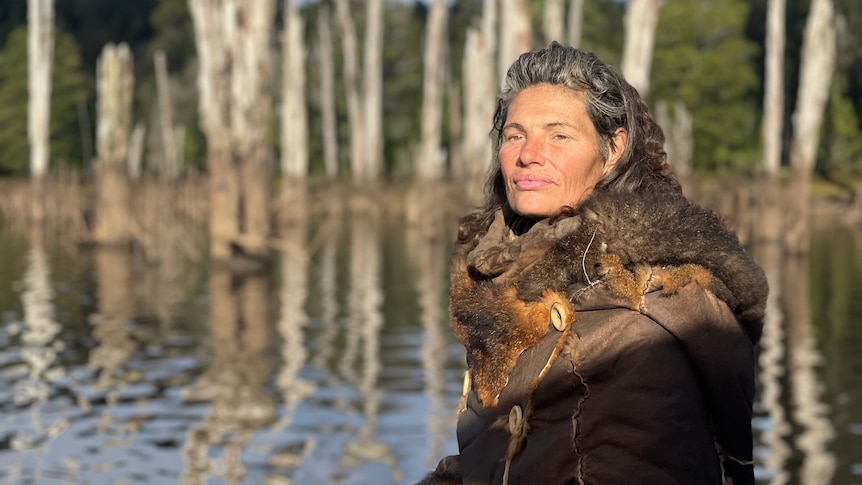 woman wearing possum fur coat sitting in wetland environment