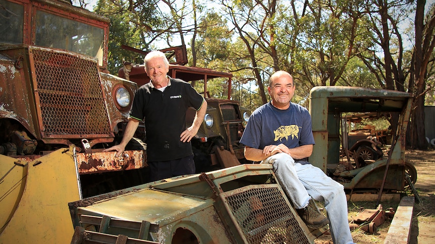 Rob Wilson and Gordon Ibbett sit on some old trucks on their property.