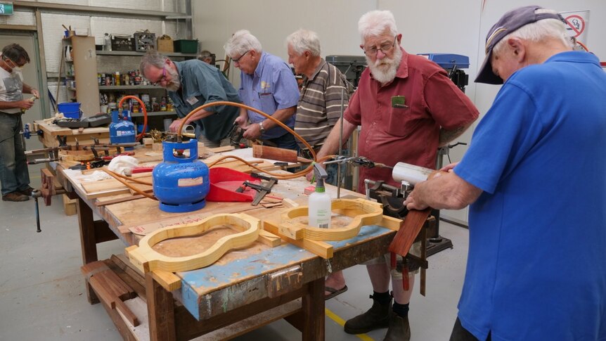 Group of older men working at a woodworking bench