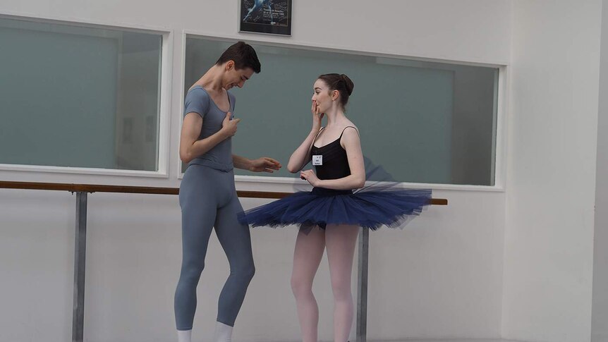 A male and female ballet dancer laughing together.
