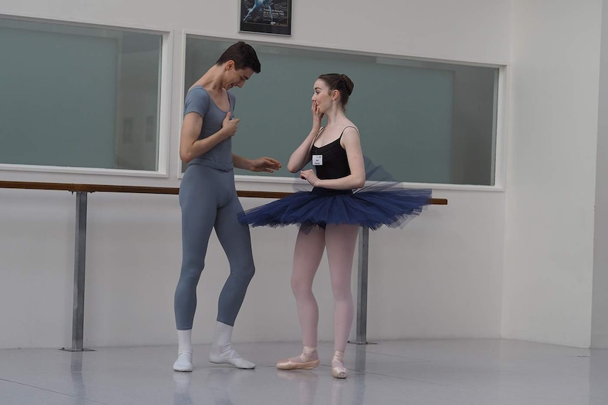 A male and female ballet dancer laughing together.