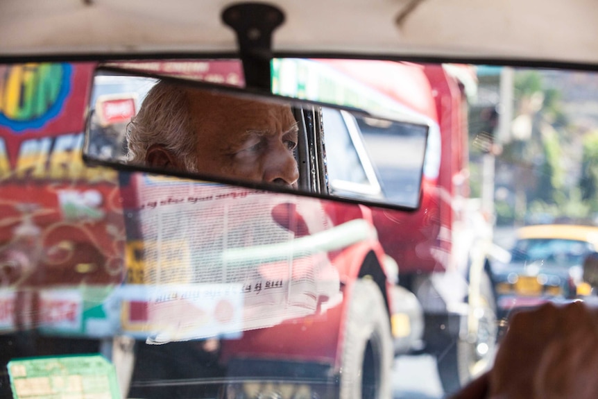 Older man driving a car and looking in the rear-view mirror