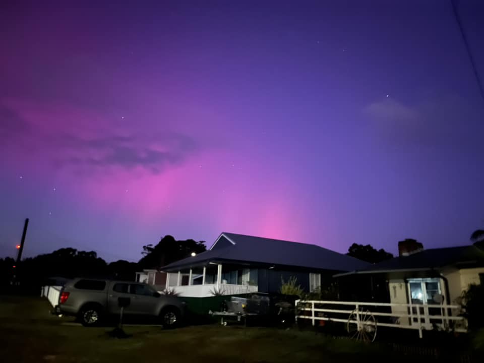 A brilliant blue and purple sky above a house and car.
