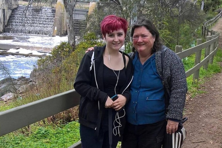 woman and daughter, standing and smiling near a water feature