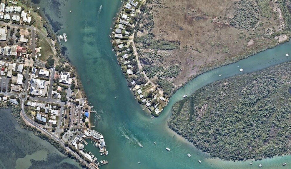 Boats leave white lines of wake behind them. Little rectangles show the roofs of houses on prime waterfront real estate. 