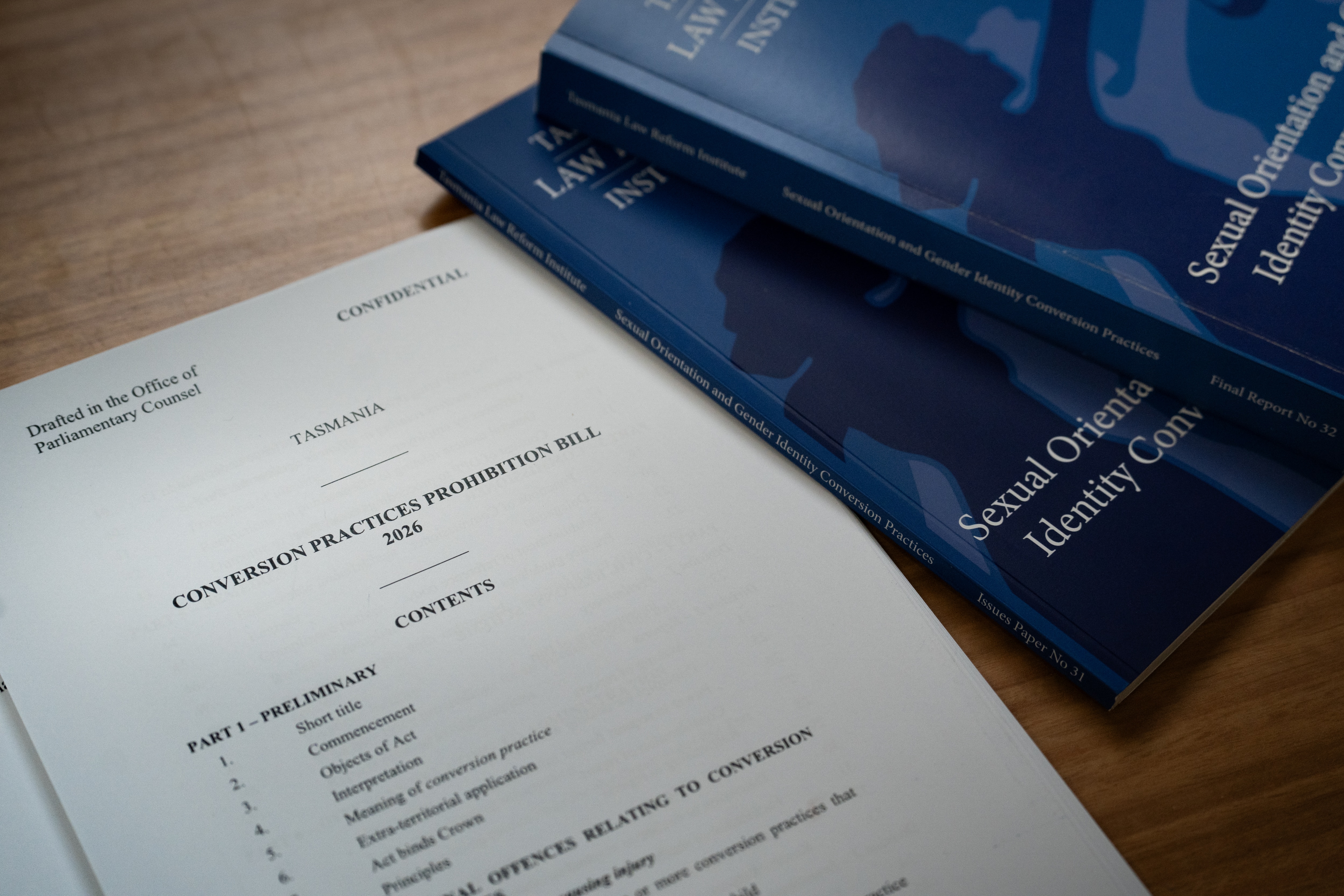 A proposed bill titled Conversion Practice Prohibition Bill sits on a desk next to some blue legal books