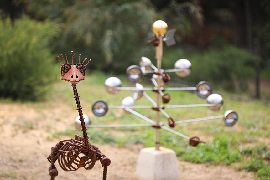 A rusted emu sculpture with an odd, metal sculpture in the background.