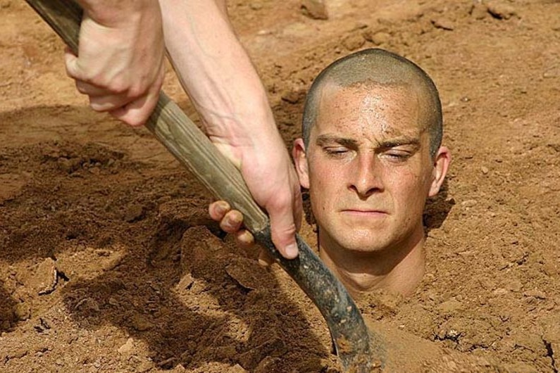 Bear Grylls is buried up to his neck in earth