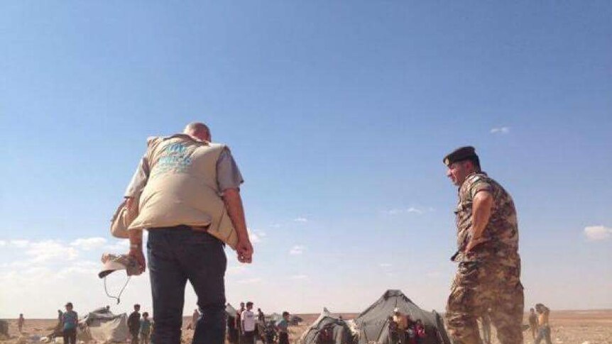 Andrew Harper walks to a refugee tent, with an armed soldier