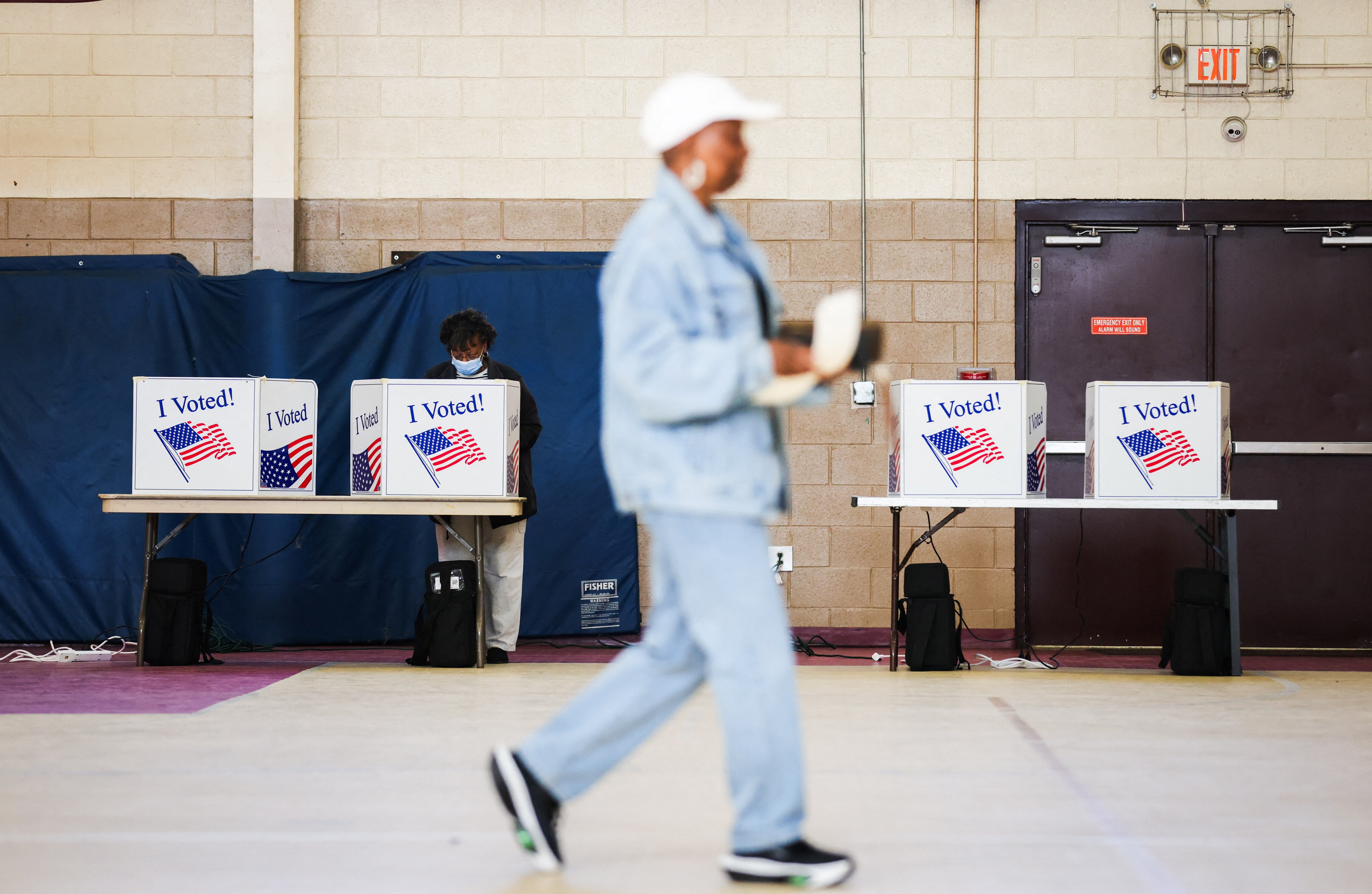 A person walks past a row of boxes labelled with an American flag and "I voted".