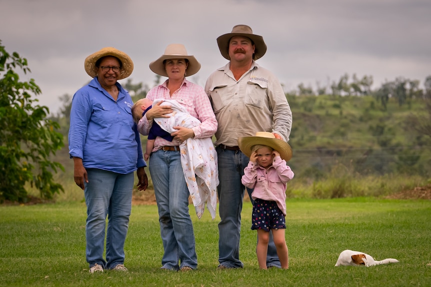 Photo of three adults and two children smiling on a property.