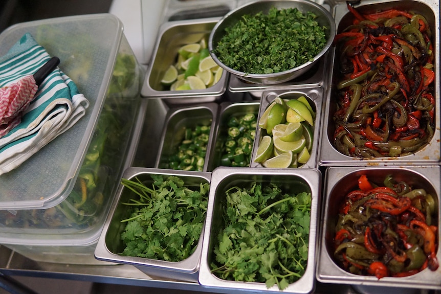 Fresh herbs, chillies, limes and fried capsicum in dishes.