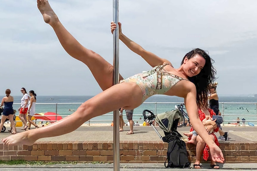 Amber Manto doing pole fitness along Bondi Beach.