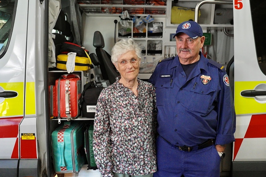 Ray stands in uniform in front of an ambulance, with his arm around wife Maureen.