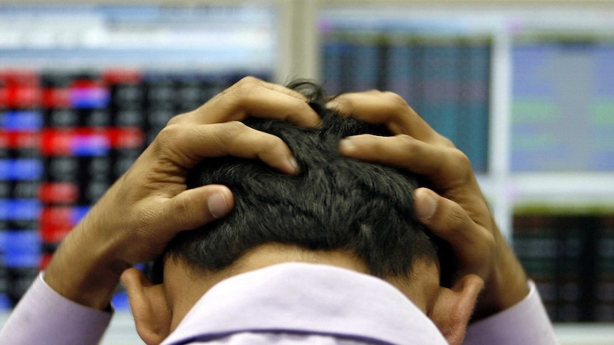 A Wall Street trader holding his head after a bad day.