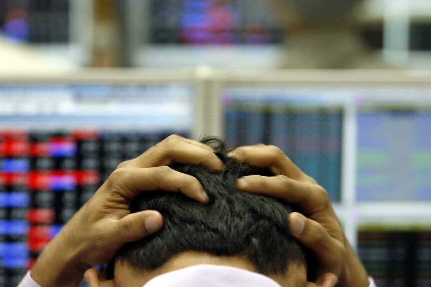 An image of a Wall Street trader holding his head after a bad day.