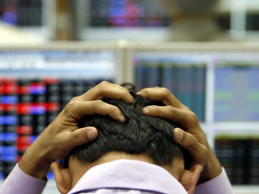 A Wall Street trader holding his head after a bad day.