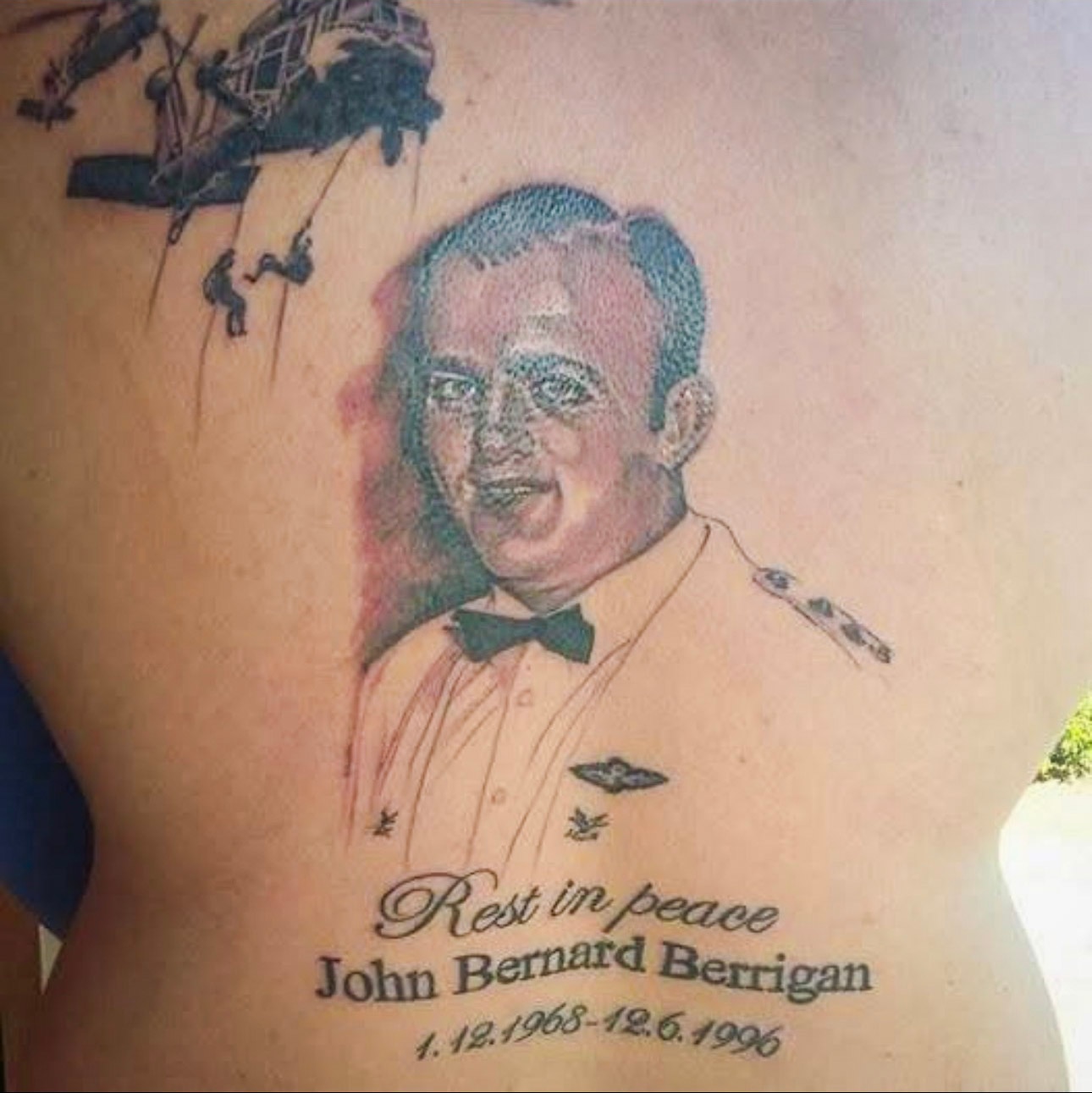 A tattoo if a portrait of a man with his name, date of birth and date of death as well as  a helicopter.