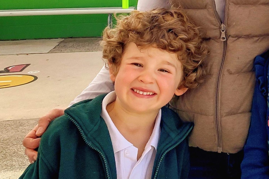 A young boy with curly hair, smiles.