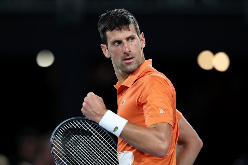 Novak Djokovic clenches his fist and looks back over his shoulder