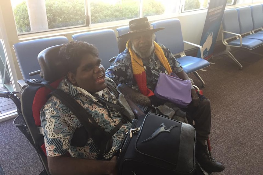 A wheelchair-bound boy and his friend, an older man, at an airport lounge.