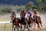Four horses and jockeys running in a country race