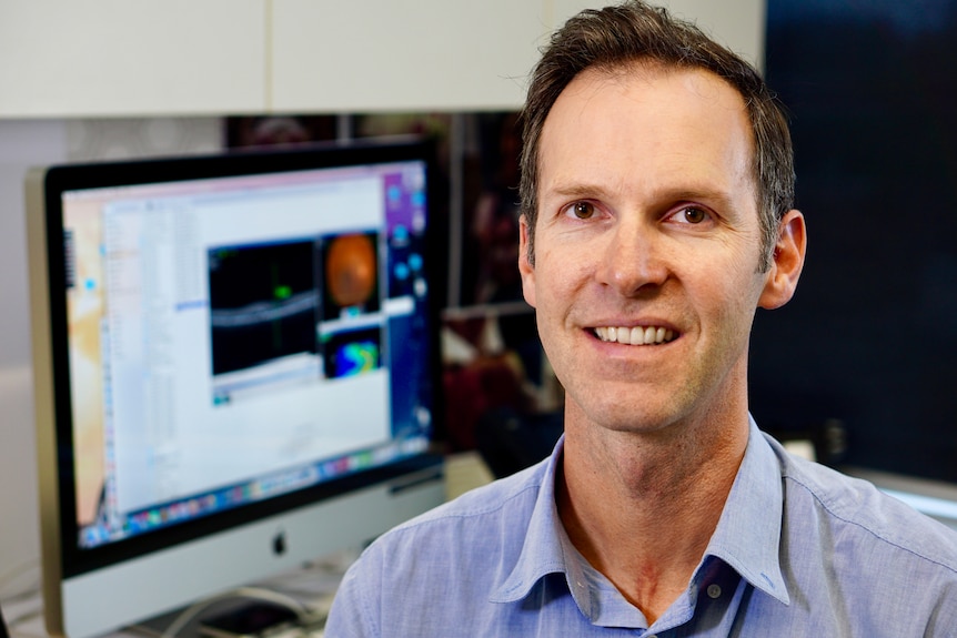 A head and shoulder shot of Dr Angus Turner, with a computer screen in the background.