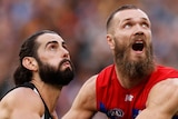 Brodie Grundy and Max Gawn hold on to each others arms and look up