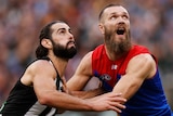 Brodie Grundy and Max Gawn hold on to each others arms and look up