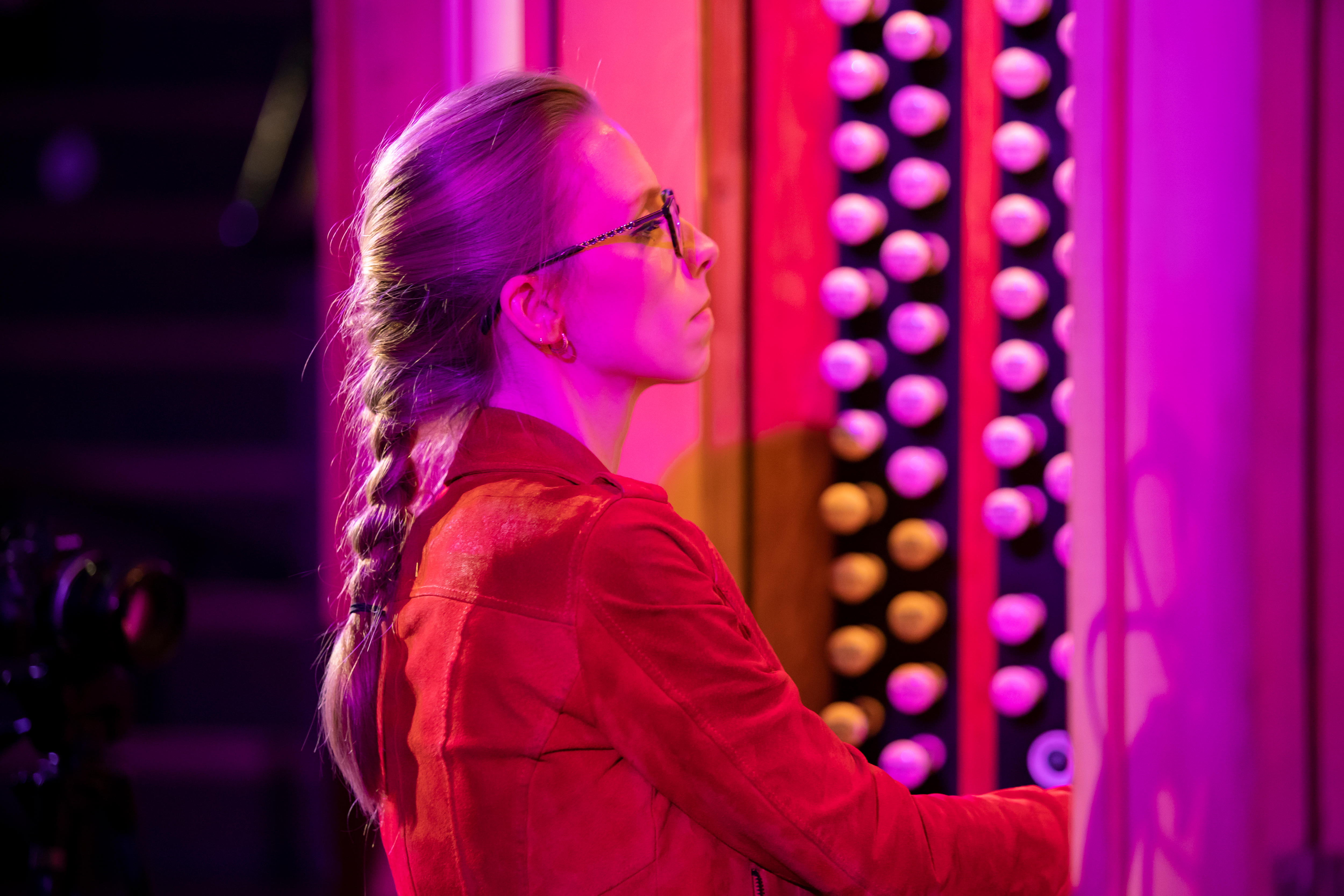 Anna Lapwood playing the organ, bathed in red and purple light.