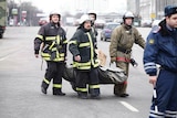 Firemen carry away the remains of victims
